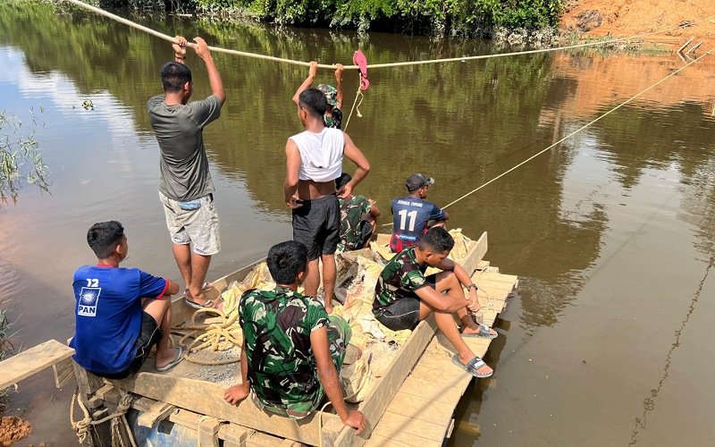Personel Kodim 0914 Tana Tidung dan Warga Gotong Royong Angkut Batu Koral Seberangi Sungai demi Percepat Pembangunan Jembatan